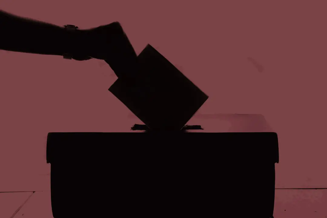 Mão depositando uma cédula em uma urna